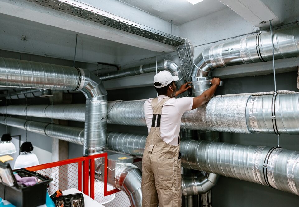 Worker,Installing,Ventilation,Ductwork,In,Industrial,Setting,During,Daytime,At